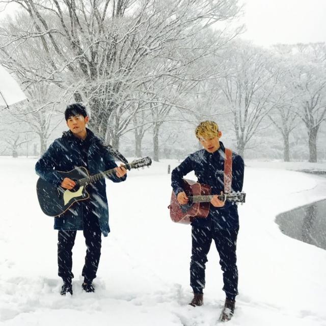 这是周杰伦和杨瑞代为了新mv在雪中拍摄的场面,两人都拿着吉他弹琴.