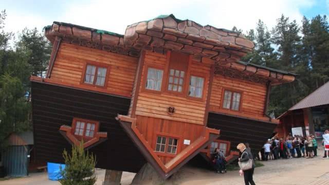 在波兰的神慕巴克村,一座上下颠倒的房屋躺在绿水青山之间,周围都是